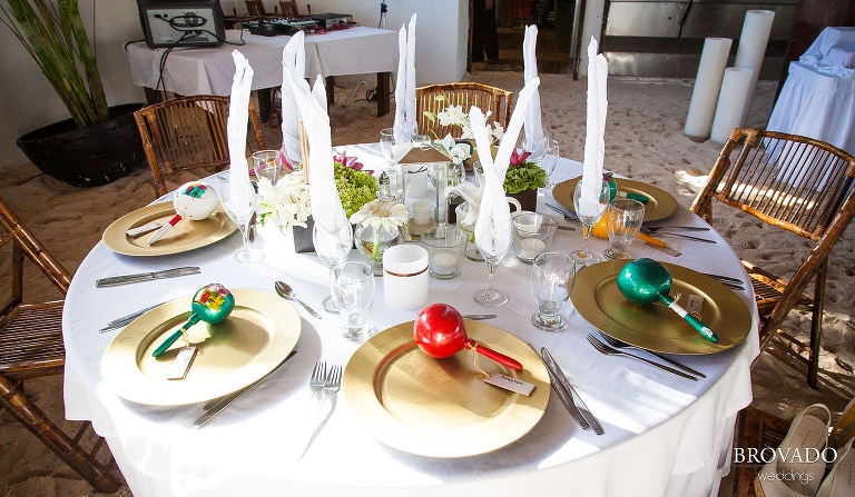 wedding reception dinner tables set with gold plates and maracas