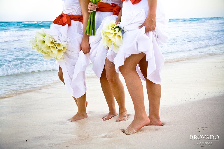 bridesmaids show off sandy feet at beach wedding