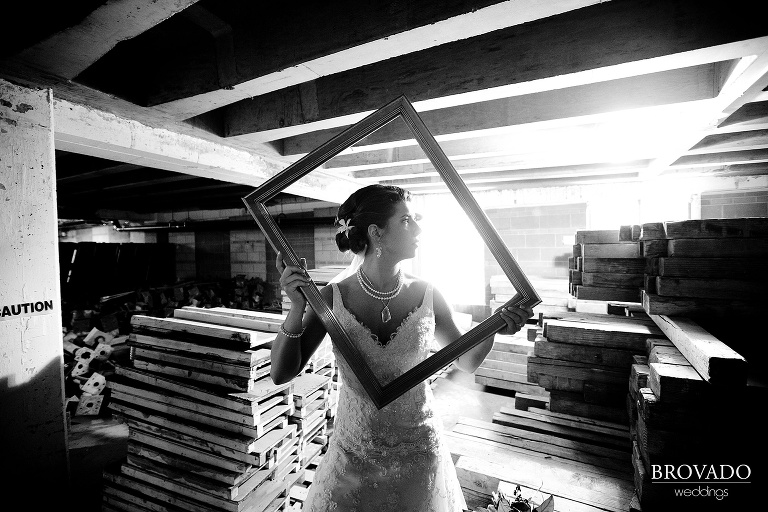 bride poses behind picture frame in black and white