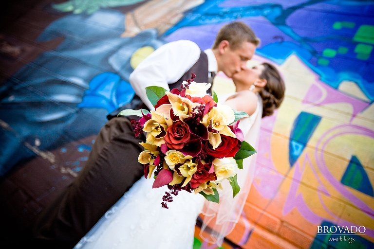 bouquet takes up the foreground while the bride and groom kiss in the background