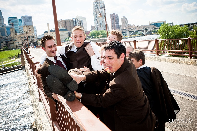 groomsmen pretending to throw the groom over the stone arch bridge