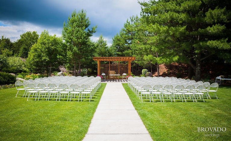 white wedding ceremony chairs set up on a green lawn