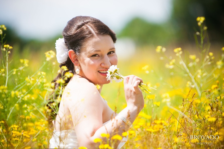 bride smiling and smelling a flower in a field