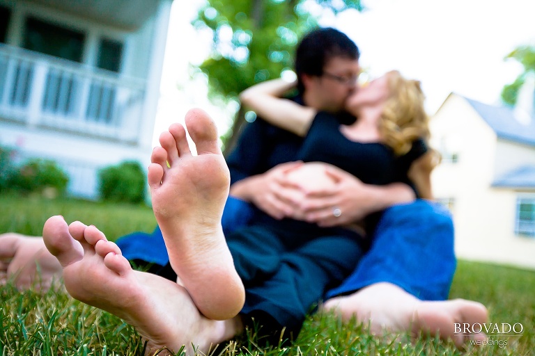maternity photo shows couple kissing with woman's feet in foreground