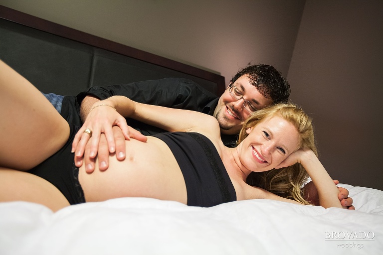 pregnant couple embrace in bed