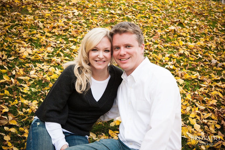 couple sit among fall leaves