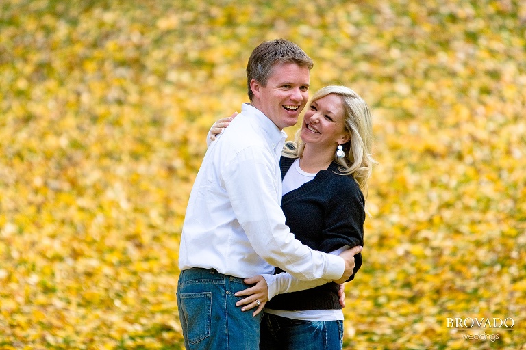 couple embraces in front of yellow leaves
