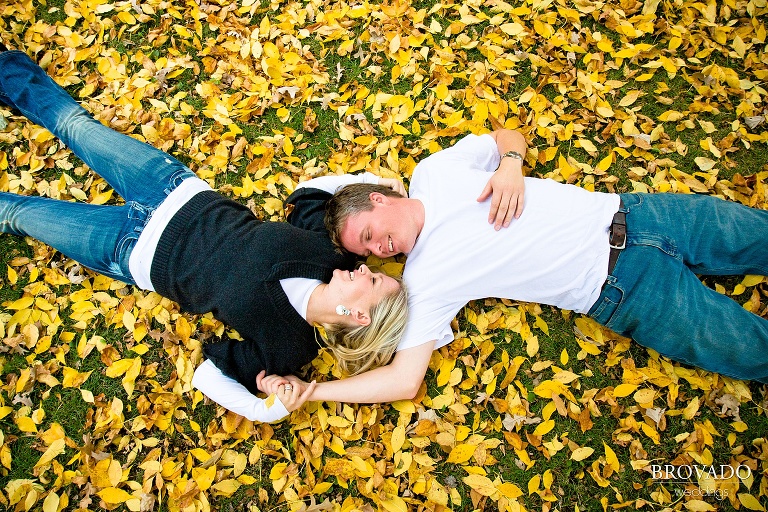 couple poses laying head to head on fall leaves