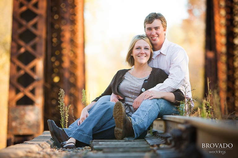 couple sit and pose along railroad tracks