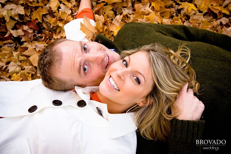 engaged couple lays in the leaves