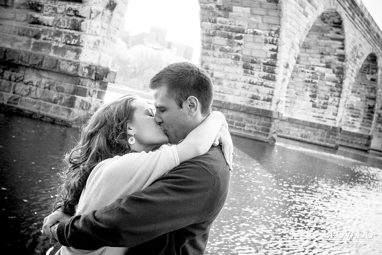 couple kiss under stone arch bridge