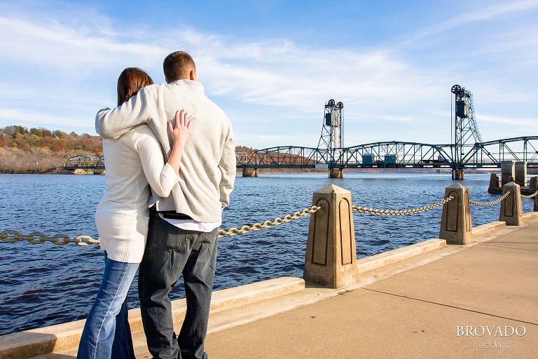 engaged couple embraces in front of stillwater lift bridge