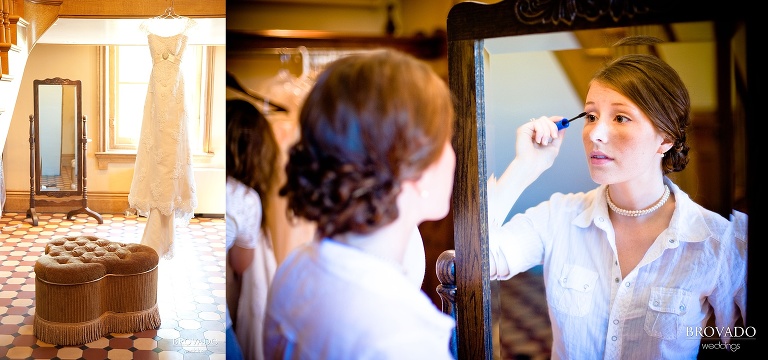bride putting on makeup while her dress hangs in the background