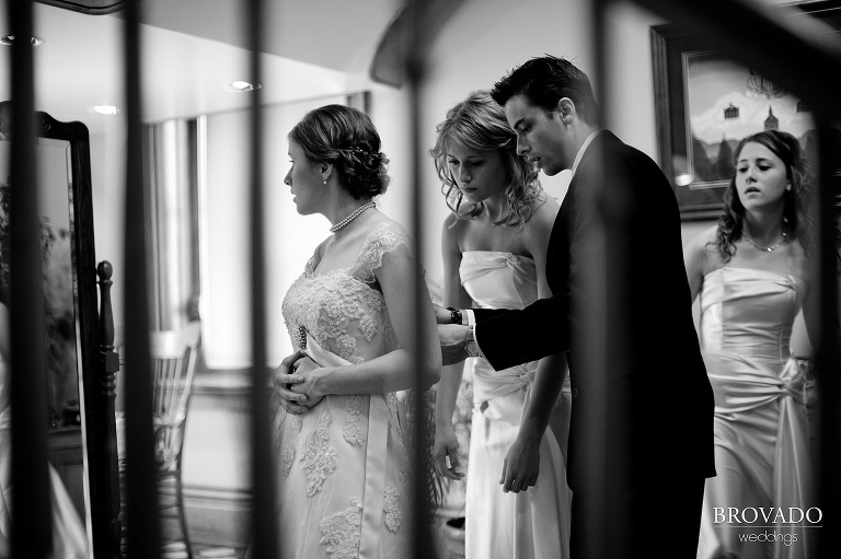 wedding party helping the bride tie up her dress