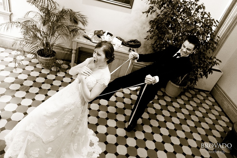 man pulls on the back of bride's dress while she jokingly screams