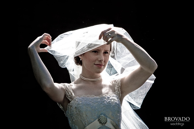 bride fixing her veil as it blows in the wind