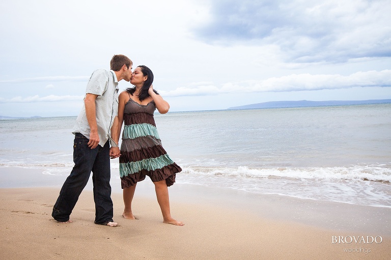 couple stops on the beach to kiss in front of the ocean