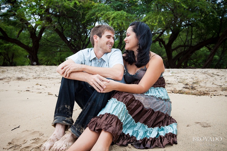 couple smiling at each other while sitting on the beach