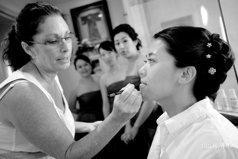 bridesmaids look on while bride gets lipstick applied