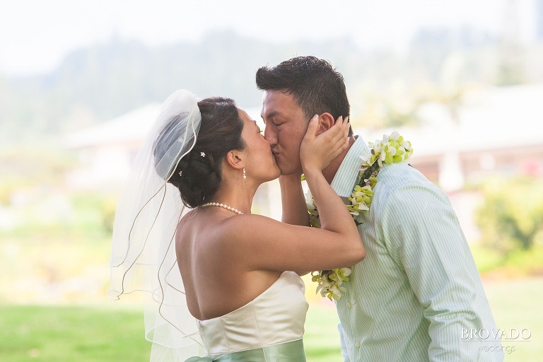 bride holds groom's face during a kiss