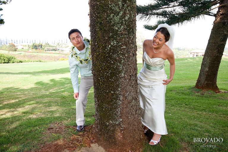 bride and groom peeking around opposite sides of a tree