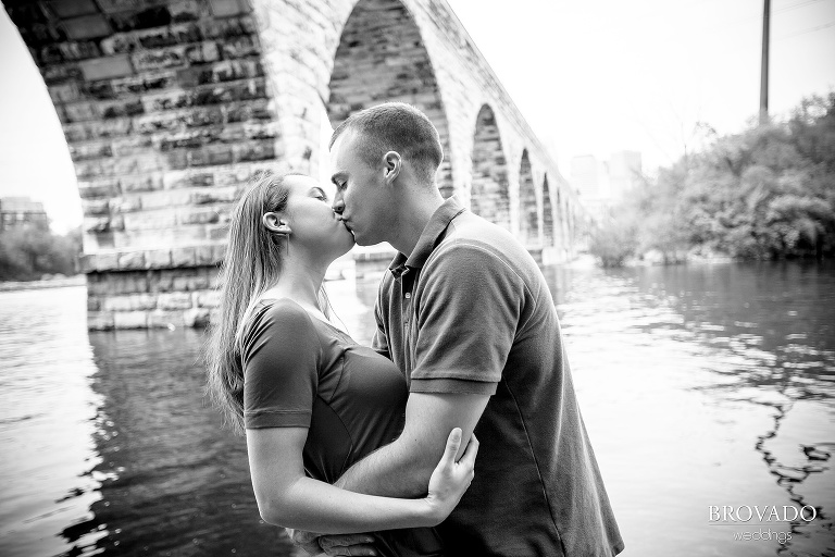 engaged couple kissing in front of stone arch bridge