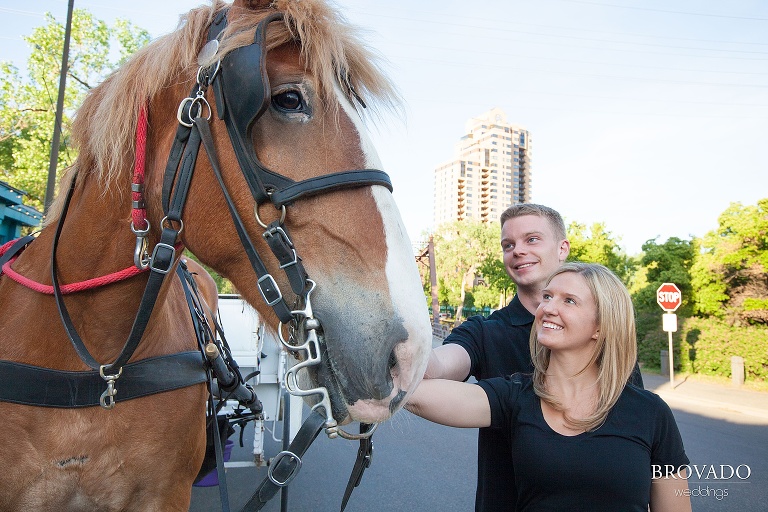 two people smiling while petting a horse