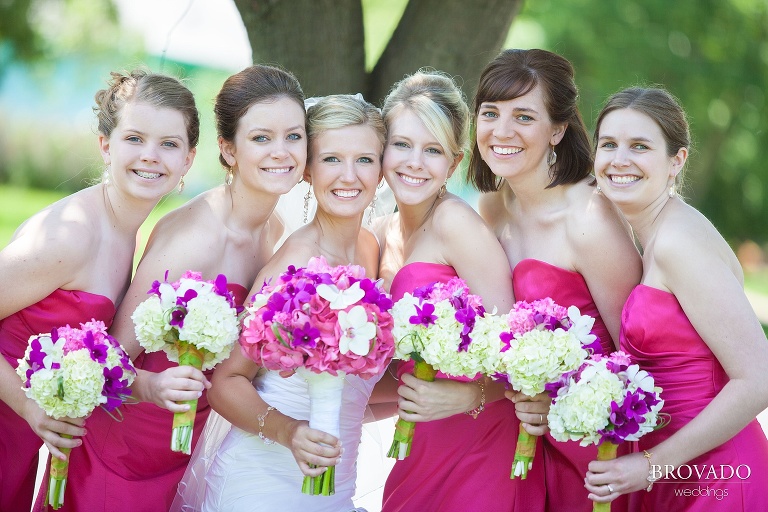 bride poses with her bridesmaids in bright pink dresses