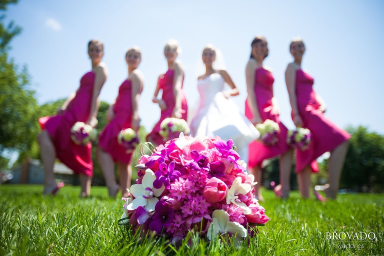 bridesmaids pose behind a pink bouquet