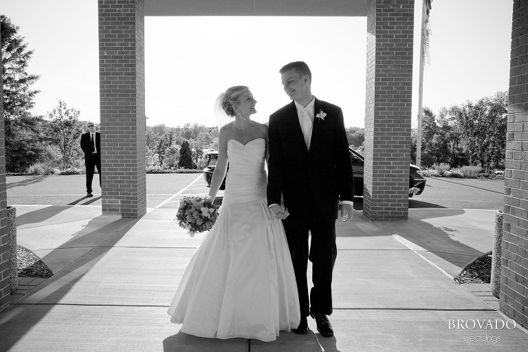 black and white photograph of bride and groom walking and holding hands