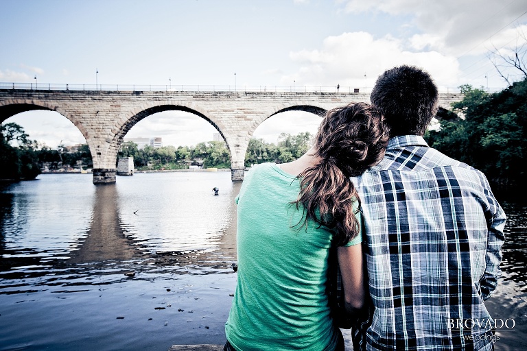 fiances sitting in front of the stone arch bridge