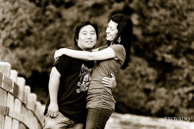 fiances goofing off on wooden bridge in sepia engagement photo