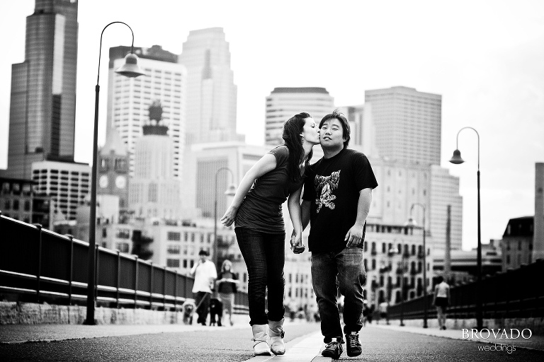 engaged couple holding hands on stone arch bridge in black and white photograph