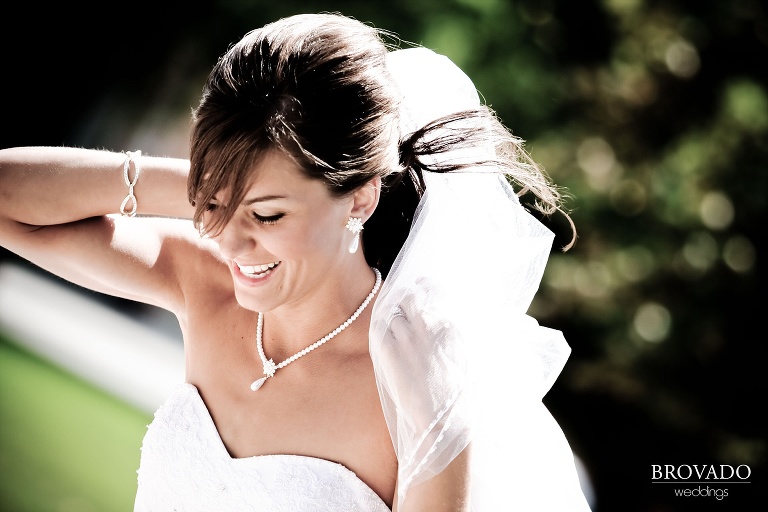 photograph of bride smiling while holding her veil on a windy day