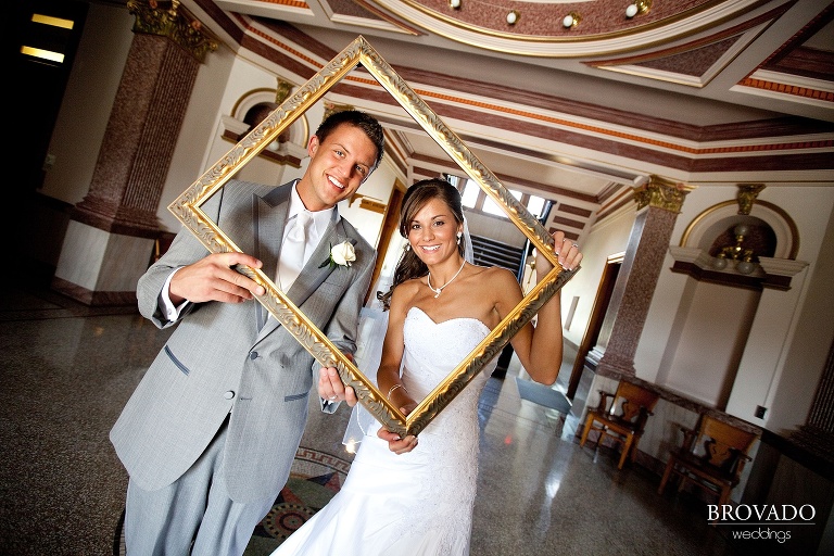 goofy wedding photograph of bride and groom smiling through a picture frame