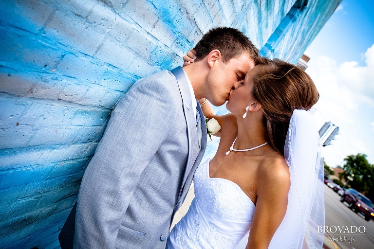 bride and groom kissing against a blue wall