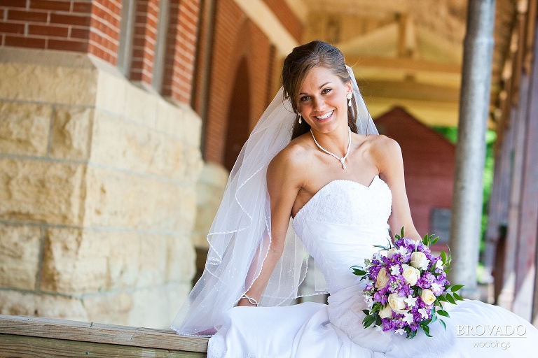 bright photograph of bride showing off her long veil and purple bouquet