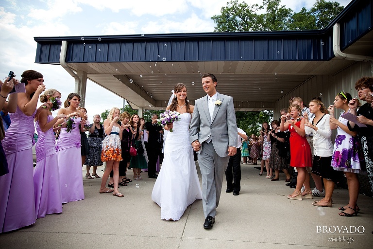 bride and groom exiting church after wedding ceremony to a bubble sendoff