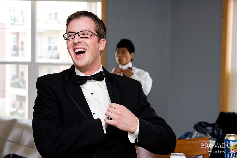 groom laughing while he adjusts his tuxedo