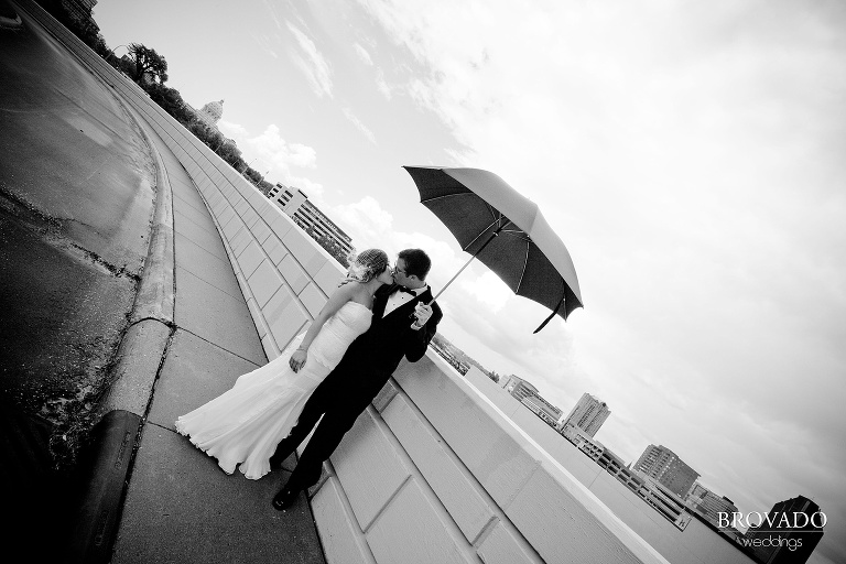 bride and groom kissing under black umbrella