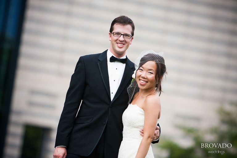 bride and groom smiling at photographer with their arms around each other