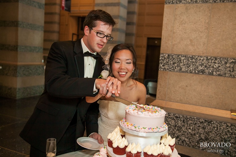 bride and groom cutting small pink sprinkle covered cake