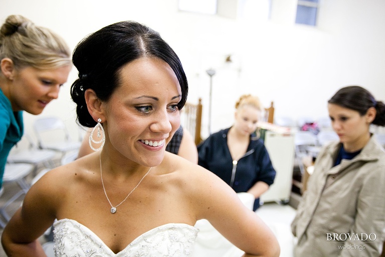 close up of bride while her bridesmaids zip up her dress