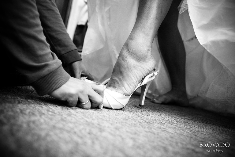 closeup black and white photograph of bride putting her shoes on