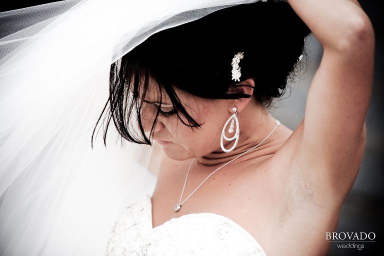 bride fixing her veil in the wind