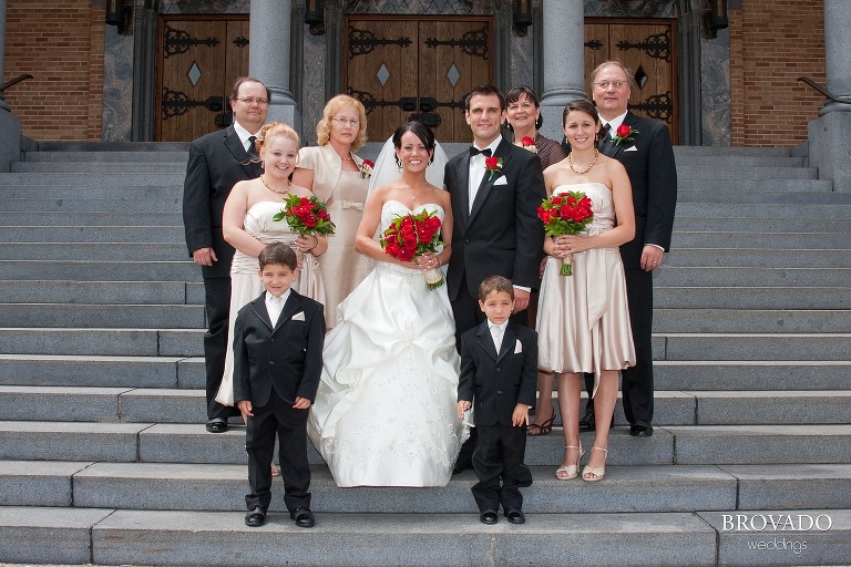 bride and groom posed with their family on church steps