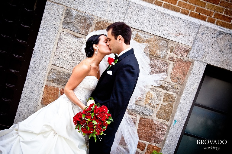 bride and groom kissing while veil blows in the background