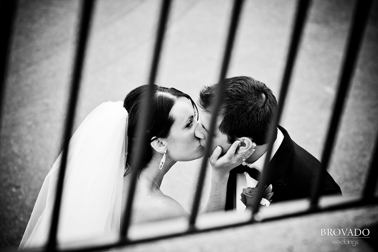 black and white photograph of bride sneaking a peek at the camera while kissing her groom