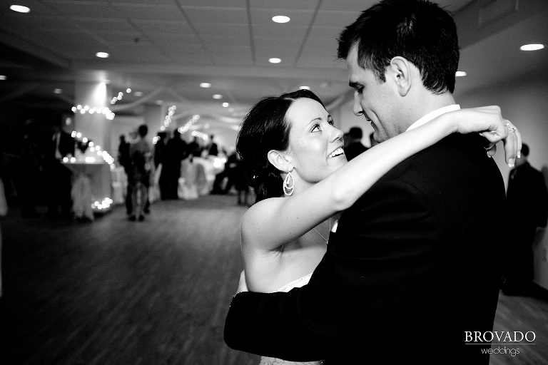black and white photograph of bride smiling up at the groom during their first dance