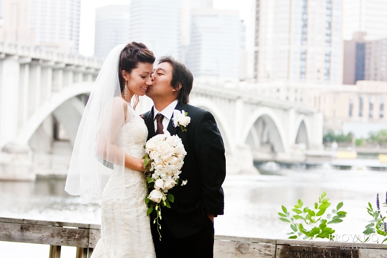groom kissing bride on the cheek in front of minneapolis skyline